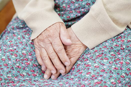 Asian elder senior woman patient sitting on bed in hospital, closeup at her hand.