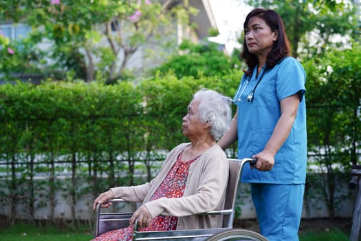 Asian elderly woman disability patient sitting on wheelchair in park, medical concept.
