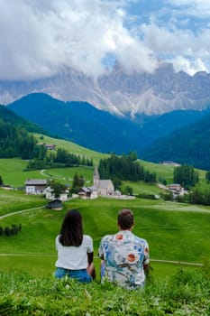 Couple viewing the landscape of Santa Maddalena Village in Dolomites Italy, Santa Magdalena village magical Dolomites mountains, Val di Funes valley, Trentino Alto Adige region, South Tyrol, Italy,