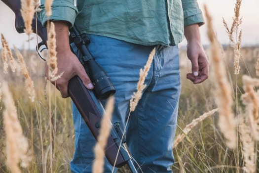 man with a rifle with a telescopic sight stands in a field