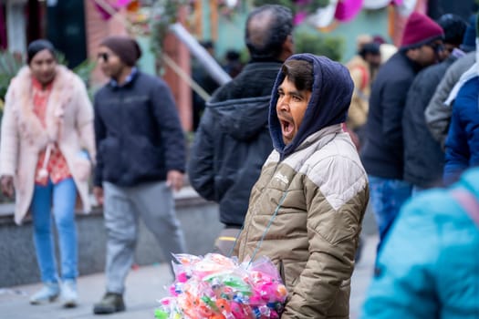 Toy vendor yawning as they search for customers on the crowded mall road in Manali