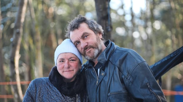 A homeless woman and a man pose in the woods in winter.