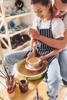 With her boyfriend or husband. Young female ceramist have a works indoors with handmade clay product. Conception of pottery