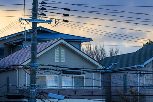 Suburban house with behind web of electrical wires at dawn