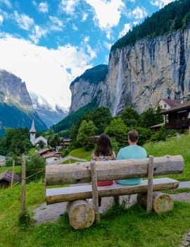 Couple of men and women visiting Lauterbrunnen valley with a gorgeous waterfall and Swiss Alps in the background, Berner Oberland, Switzerland, Europe.