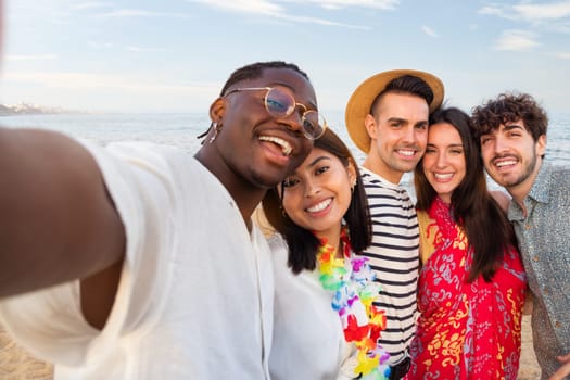 Group of happy, multiracial friends looking at camera take selfie together outdoors in the beach. Summer party. Lifestyle and happiness concept.