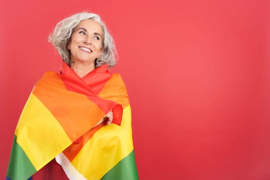 Smiley mature woman wrapped with a lgbt flag
