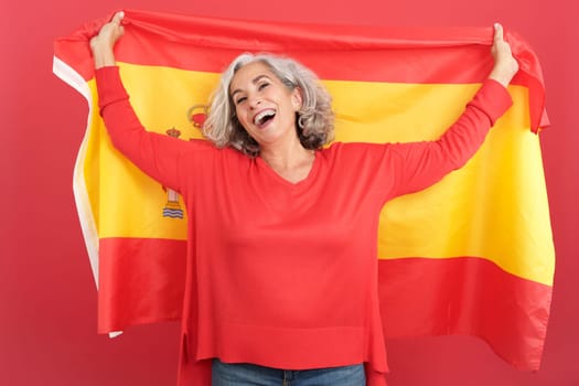 Happy mature woman raising a spanish national flag