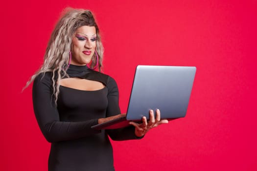 Happy transgender person standing and using a laptop
