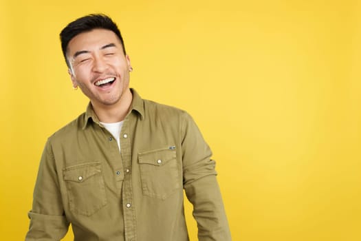 Chinese man laughing with eyes closed while standing