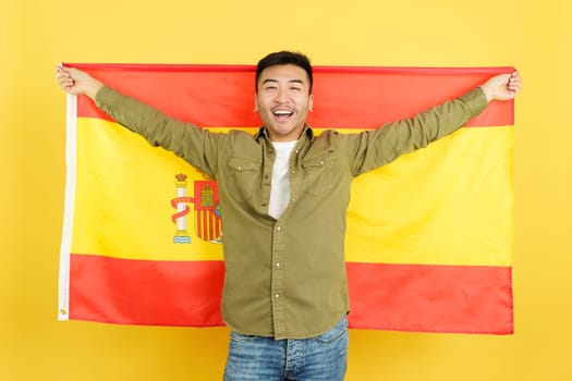 Chinese man smiling and raising a spanish national flag