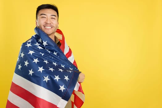 Happy chinese man wrapping with a United States national flag