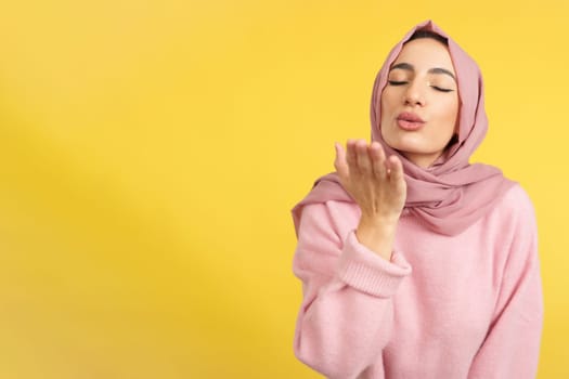Muslim woman blowing a kiss with eyes closed