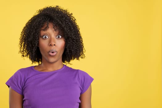Shocked woman with afro hair looking at camera