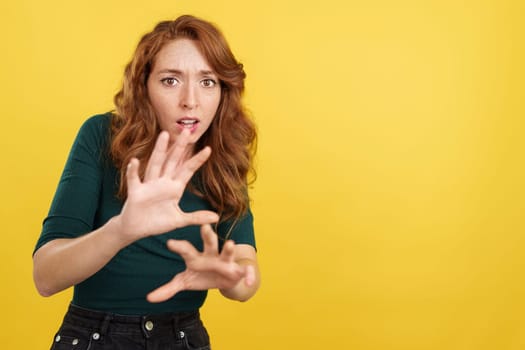 Redheaded woman gesturing with the hands in fear