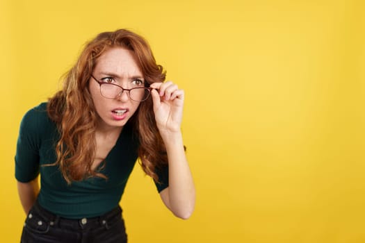 Redheaded woman with glasses spying with curiosity