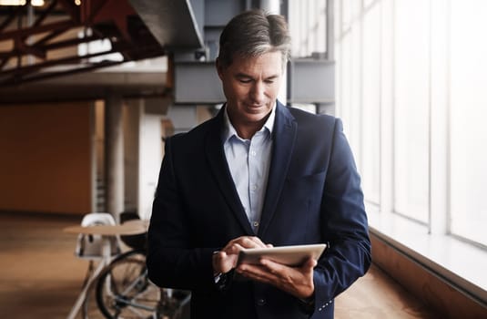 Connectivity is pivotal in todays competitive market. a mature businessman using a digital tablet in an office.