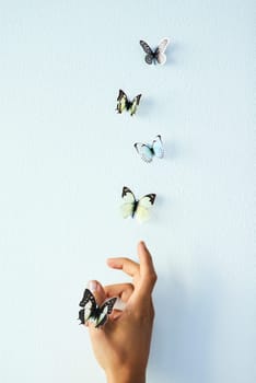 Sometimes we just have to let go. Studio shot of an unrecognizable person releasing butterflies into the air against a grey background.