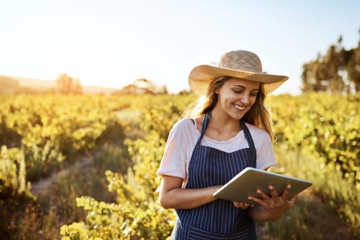 Farming in the age of the app. an attractive young woman using a digital tablet on a farm.