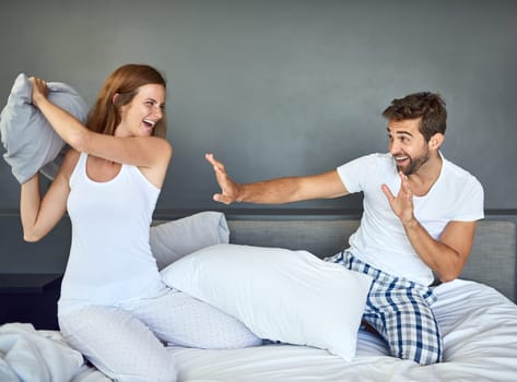 Prepare to be defeated by the pillow fight champion. a happy young couple having a pillow fight in bed.