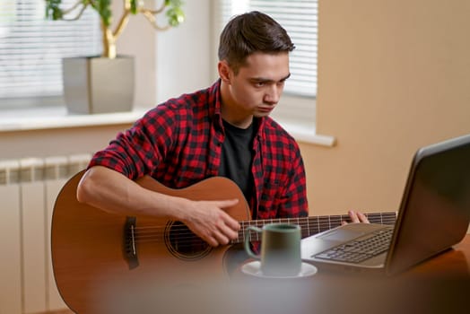 Young man learning to play guitar online