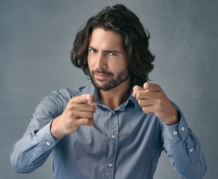 Long hair Beard Trend of the year. Studio shot of a handsome young man pointing at the camera against a grey background.