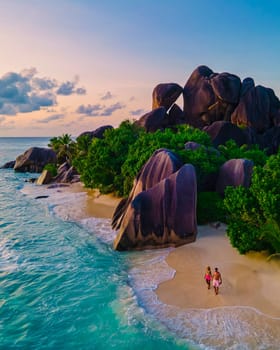 Anse Source d'Argent beach, La Digue Island, Seyshelles, Drone aerial view of La Digue Seychelles bird eye view, couple men and woman walking at the beach during sunset at a luxury vacation