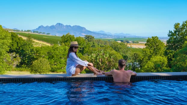 couple in swimming pool looking out over the Vineyards and mountains of Stellenbosch South Africa