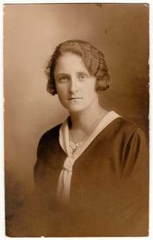 Vintage photo shows woman - portrait. Retro black and white studio photography with sepia effect.