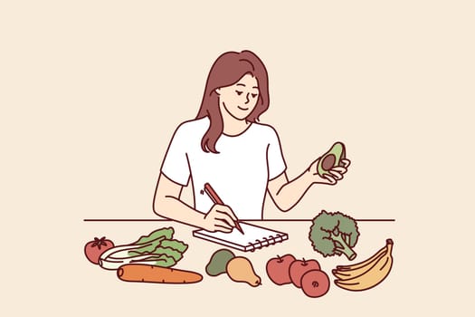 Woman near table with vegetables makes notes counting calories or making plan for new keto diet