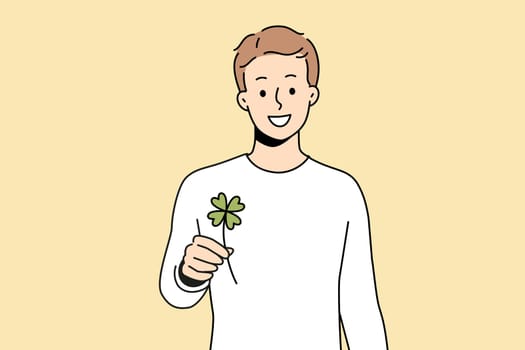 Smiling man holding clover with four leaves