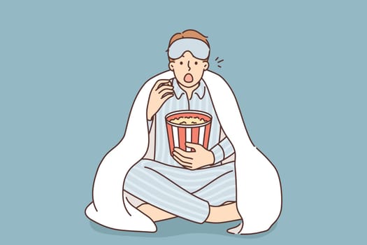 Man in pajama eat popcorn watch movie