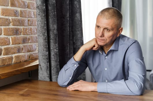 Portrait of a pensive middle-aged man sitting at a table.