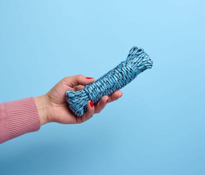 Female hand holding a textile clothesline on a blue background