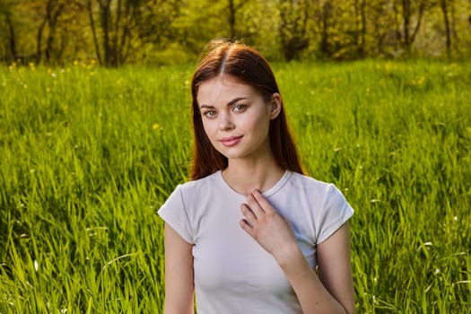 portrait of a pensive woman sitting in the grass in nature