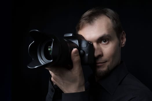 Close-up portrait of a professional photographer with a camera in the dark like a paparazzi