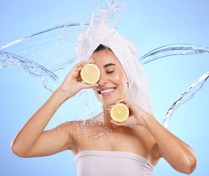 Shower, lemon and water splash with woman in studio for natural cosmetics, beauty and mockup. Happy, fruits and spa hydration with female on blue background for vitamin c, face and skincare