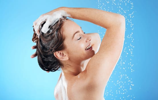 Shampoo, washing hair and smile, woman in shower on blue background for morning bathroom routine in studio mockup. Healthy haircare, water and happiness for happy beauty model cleaning in soapy foam.