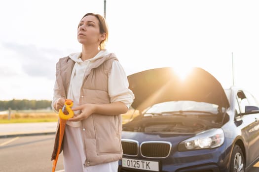 woman driver with a cable for towing a car on the background of a broken car