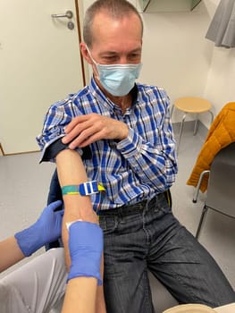 a nurse, doctor or medical technologist in blue gloves taking a blood sample