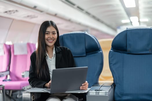 Female passenger sitting on plane while working on laptop computer with simulated space using on board wireless connection.