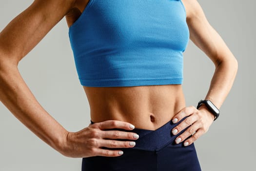 Close up of sporty strong woman body wearing sportswear on studio background