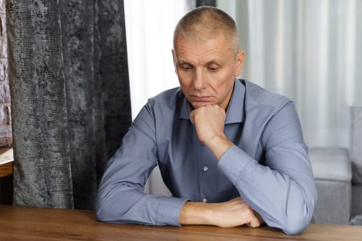 Portrait of a pensive middle-aged man sitting at a table.