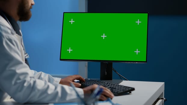 Doctor typing medical expertise on computer with green screen chroma key display