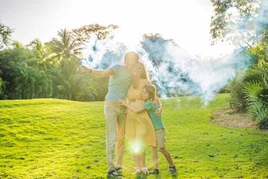 Pregnant mom, dad and son at the gender party on the golf course release blue smoke. Gender reveal announcement on the golf course. Loving family expecting baby boy. Happy moments