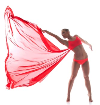 Flexible dancer posing with red cloth in studio