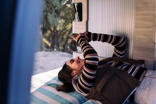 Young woman relaxing using phone in camper van