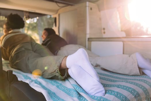 two women enjoying sunset lying in a camper van
