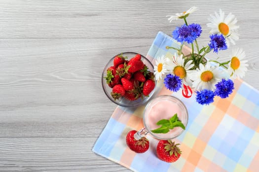 Strawberry yogurt in glass with fresh strawberries, chamomile and cornflowers