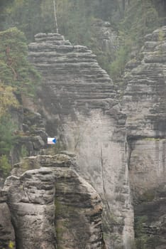 Vertical shot of sandstone formations with a Czech flag in the Bohemian Paradise in Czech Republic